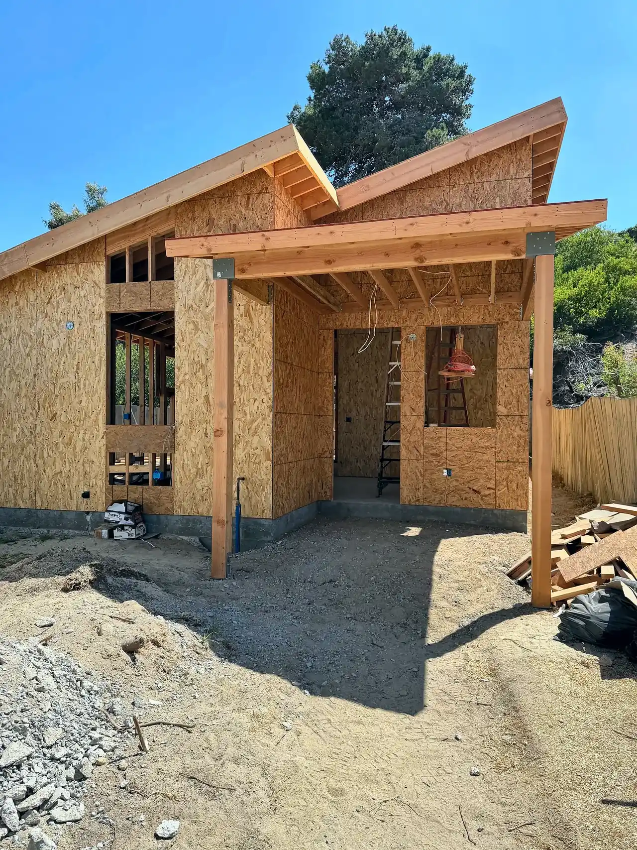 Detached ADU under construction in Del Mar, framed and sheathed, with a butterfly roof and covered entry porch