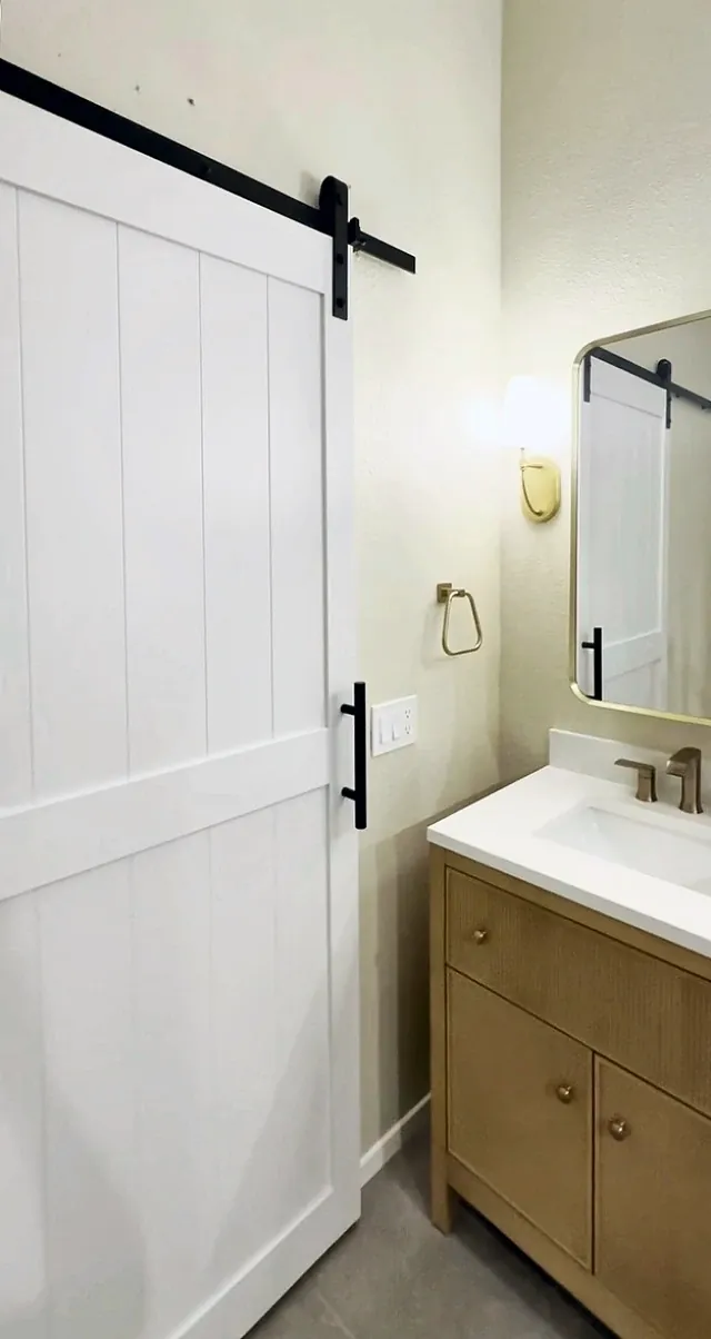 White barn door on black track hardware next to the double vanity