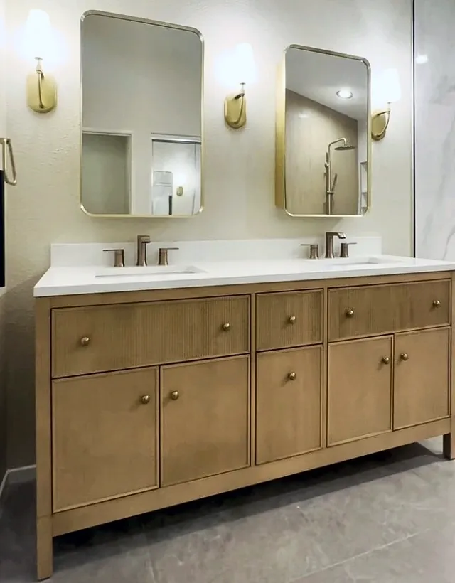 The finished vanity wall, with a light oak double vanity, two brass mirrors and three sconces