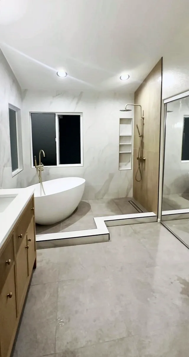 Primary bathroom looking toward the tub and shower, with the vanity on the left and a mirrored closet on the right