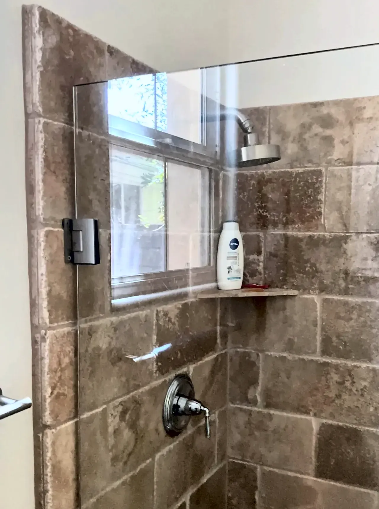 The Point Loma shower before the remodel, with brown stone tile