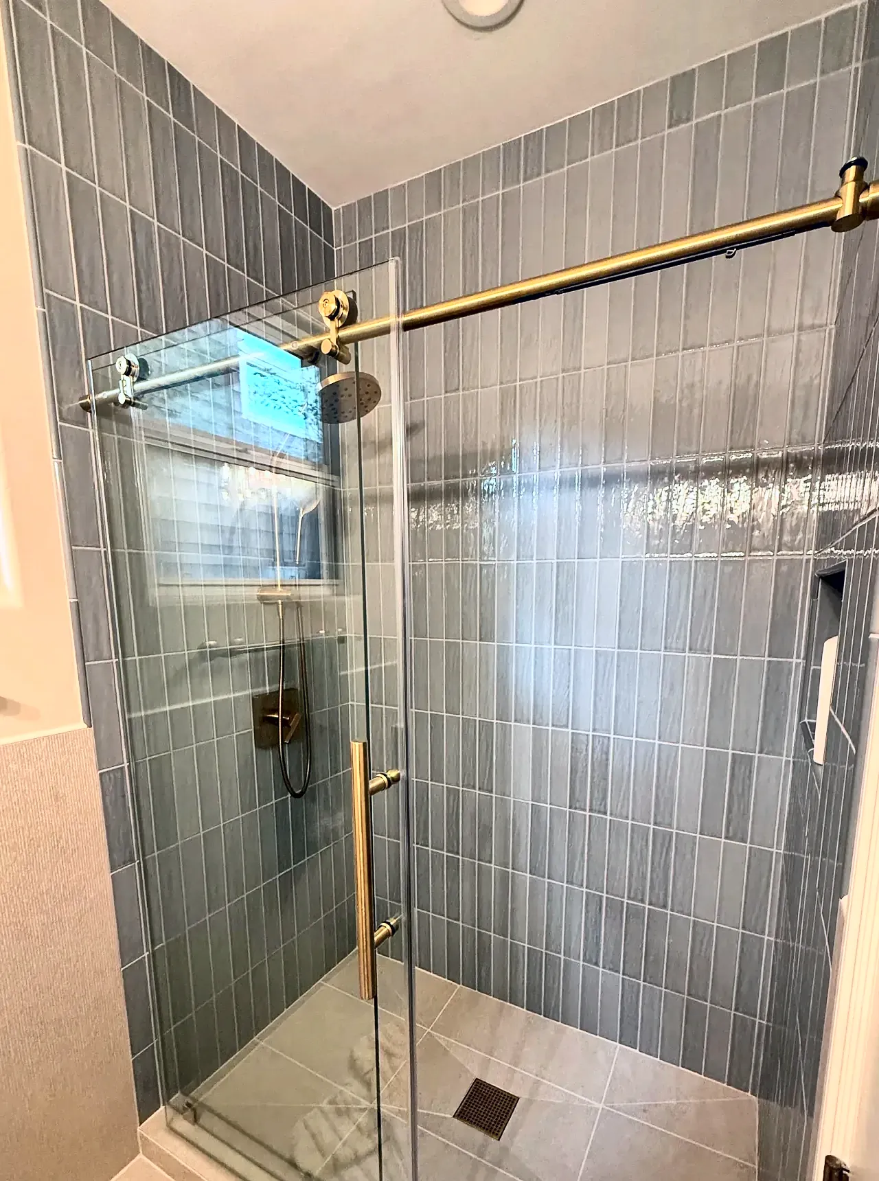 Sage vertical tile shower with a brass sliding glass door