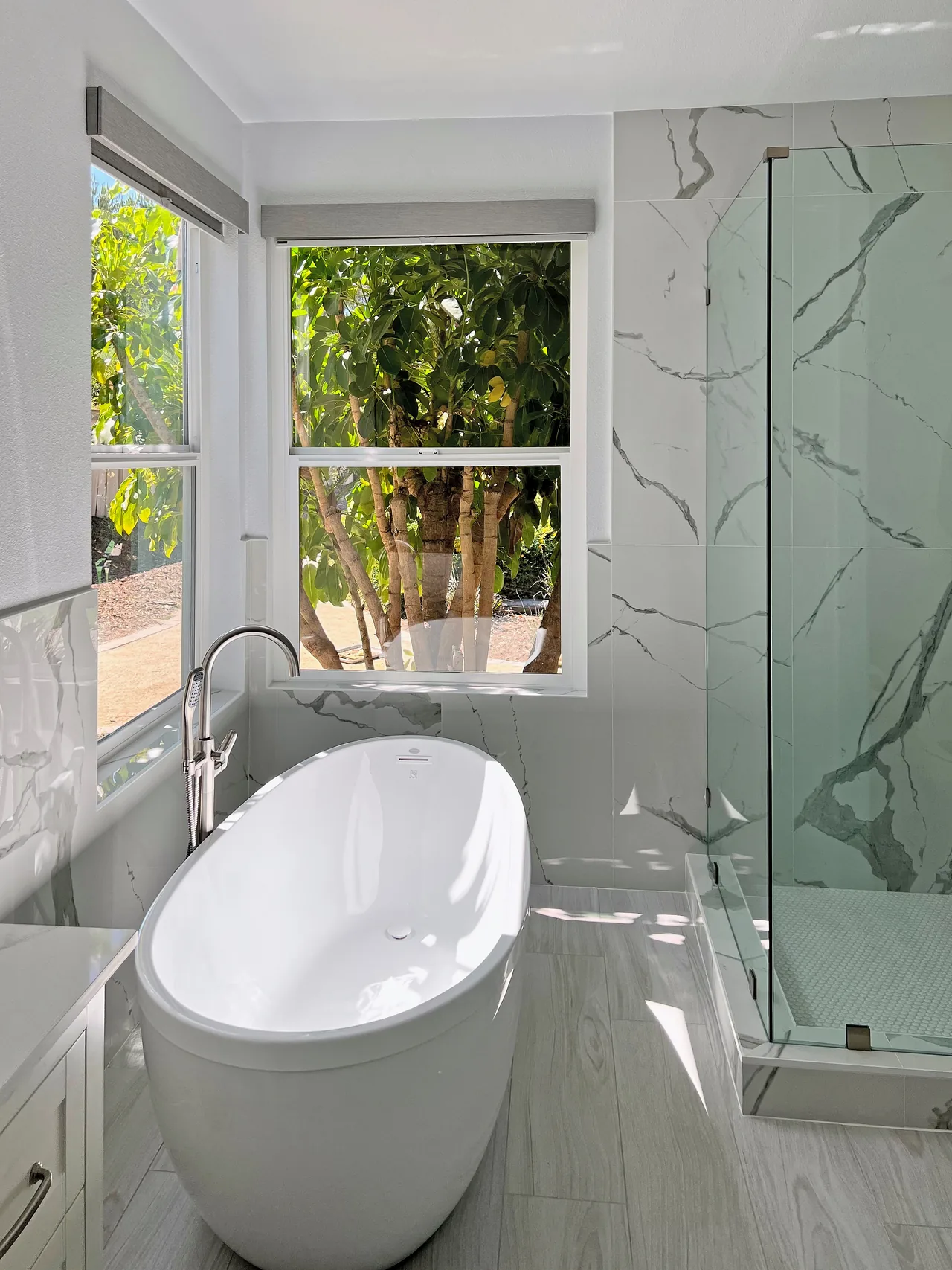 Poway primary bathroom with a freestanding tub under the corner windows and a frameless glass shower
