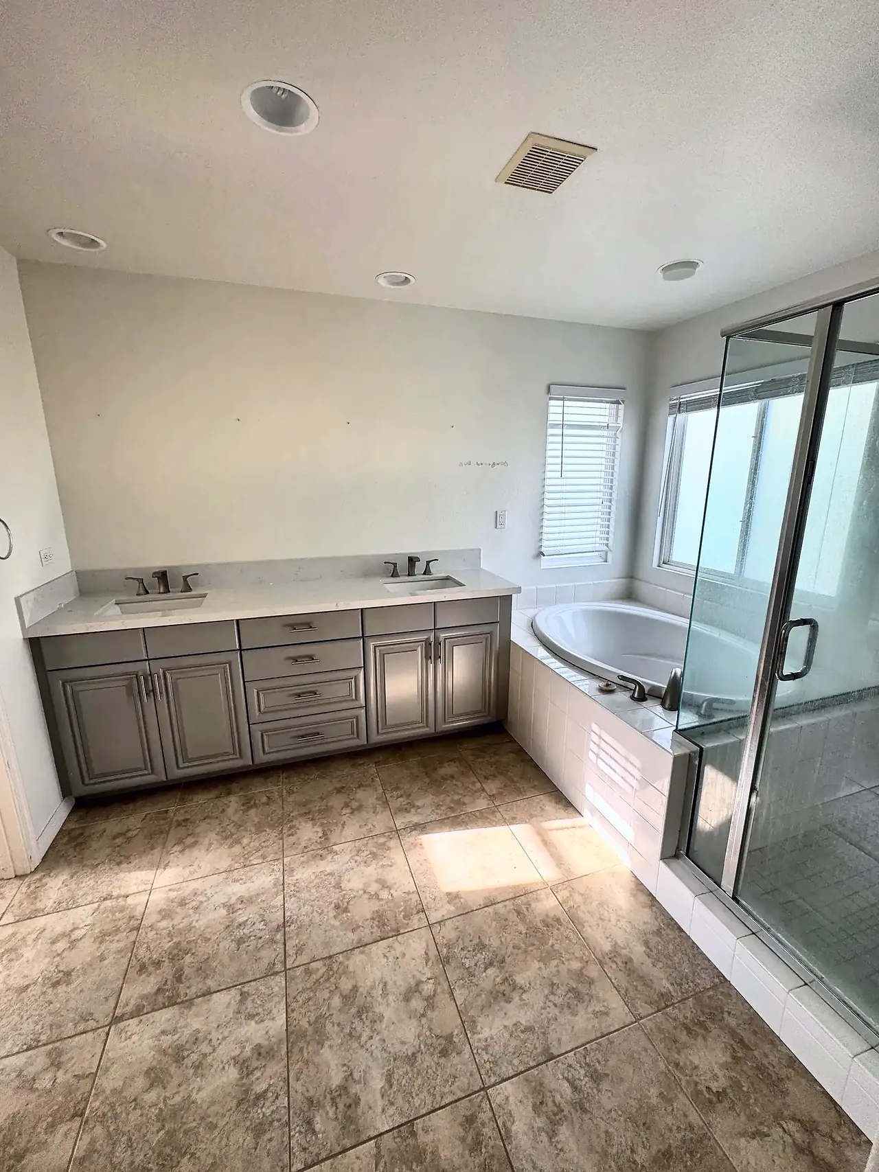 Primary bathroom before the remodel, with a raised-panel vanity and a tiled tub deck