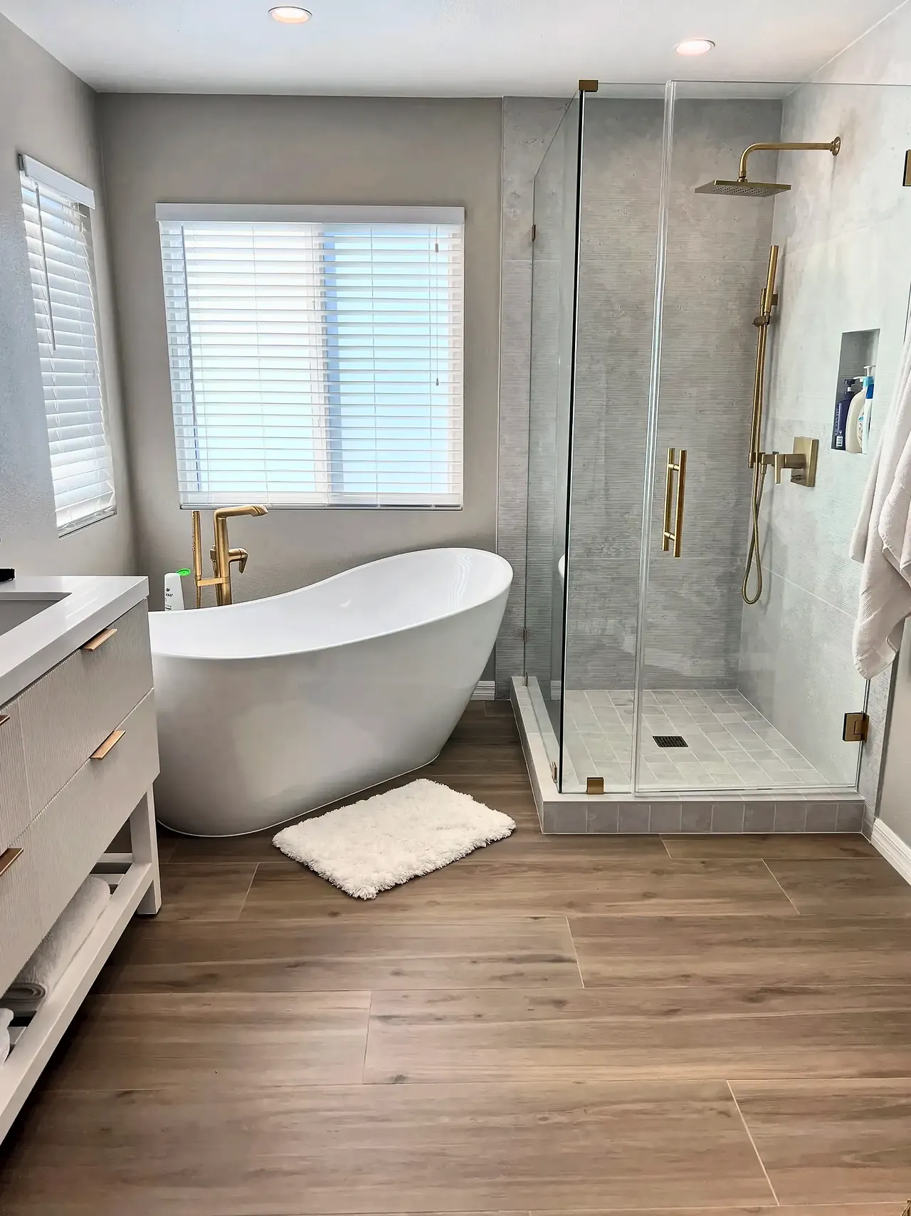 Primary bathroom after, with a freestanding slipper tub and a frameless glass shower