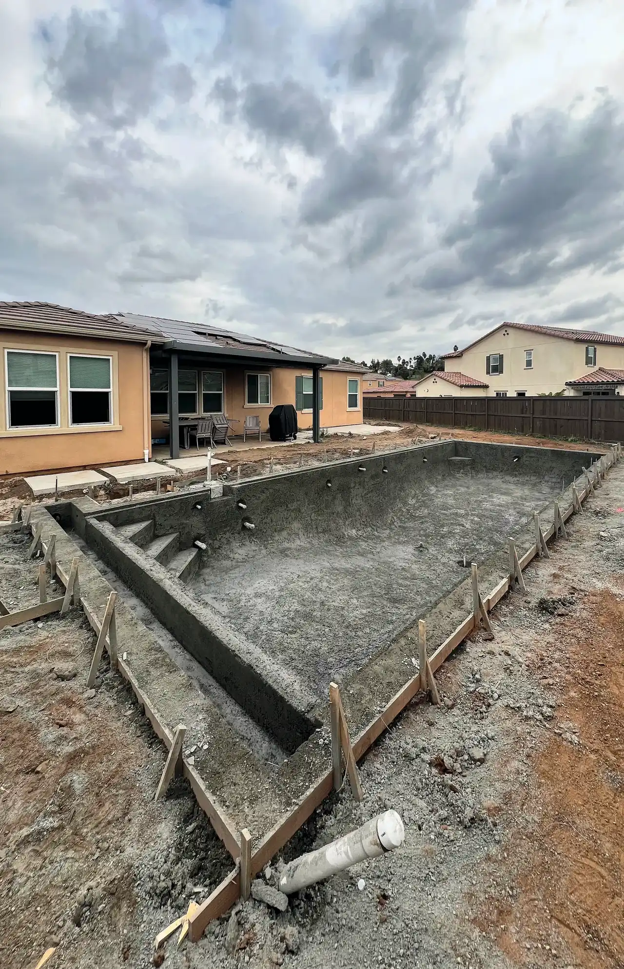 The pool shell with the house behind it