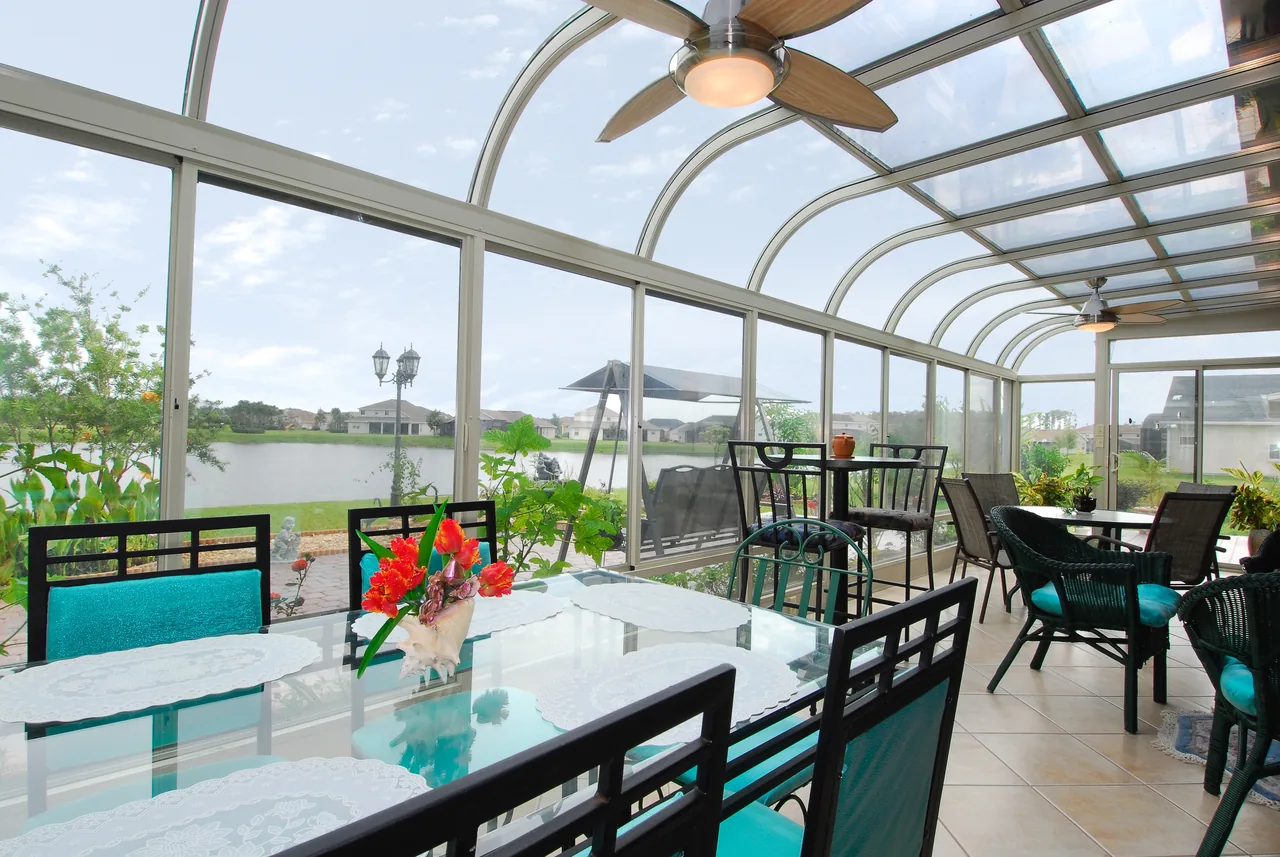 Four Seasons Curved glass roof sunroom with a dining table and a ceiling fan