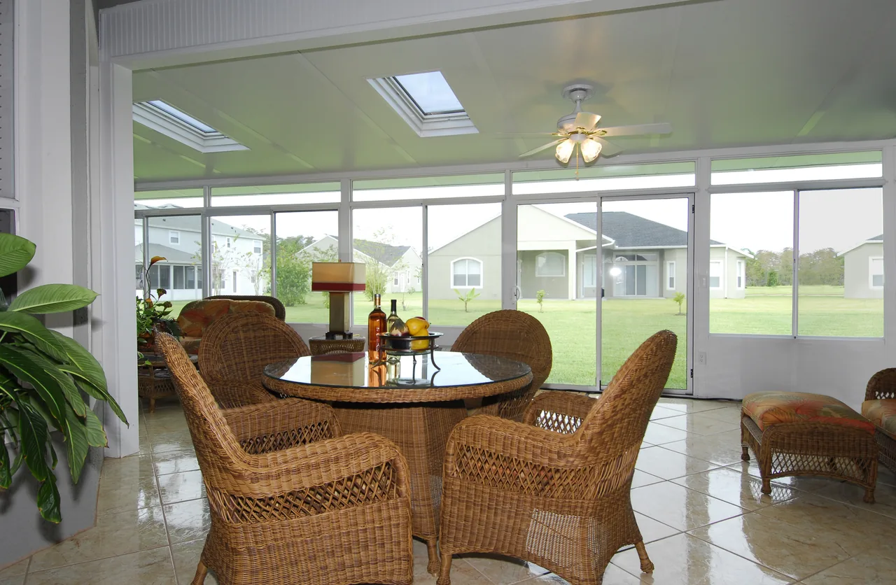 Four Seasons solid roof sunroom with skylights, a ceiling fan and a wicker dining set