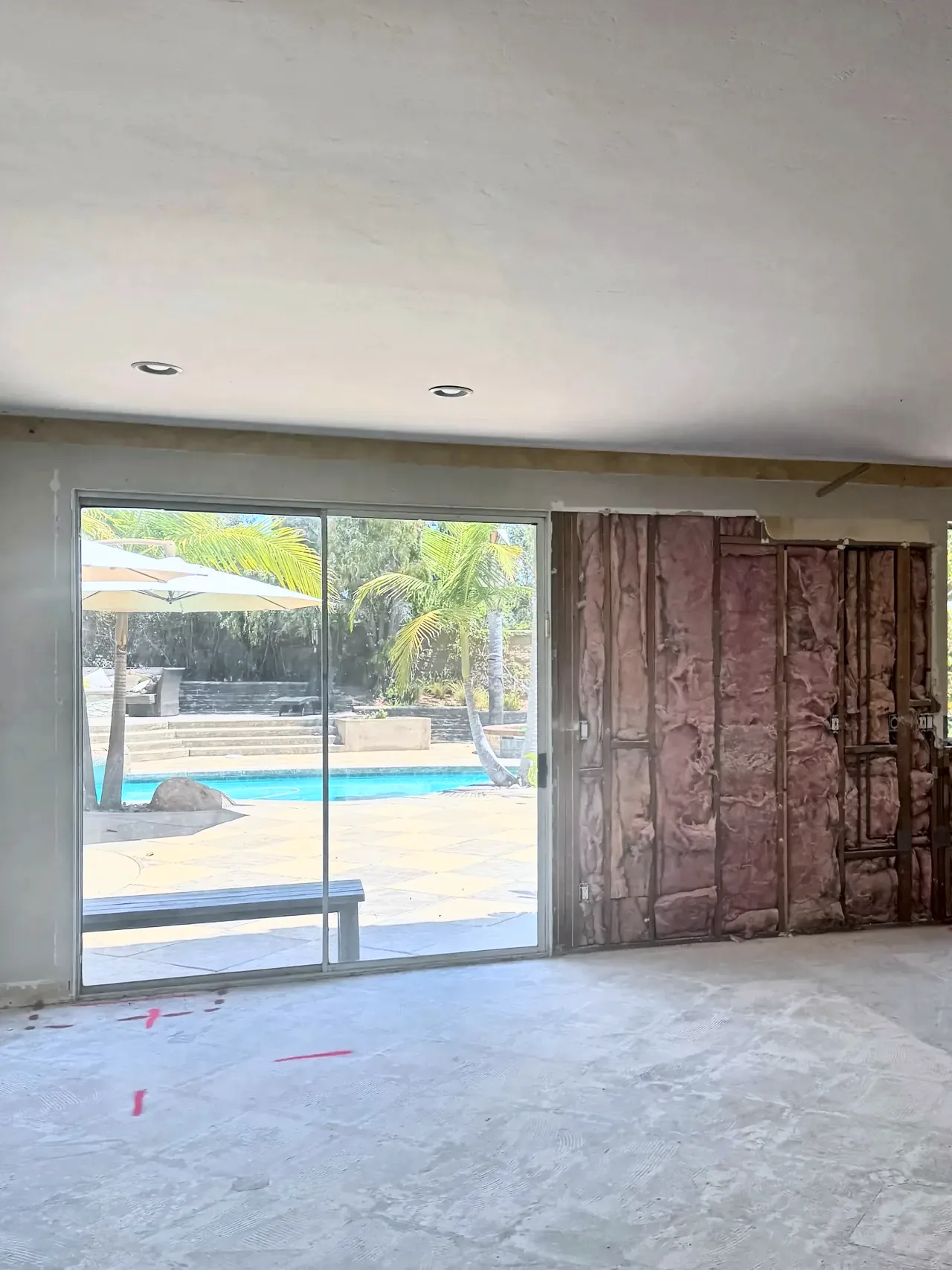 Carlsbad family room before, with an old sliding door and the wall beside it opened to the studs