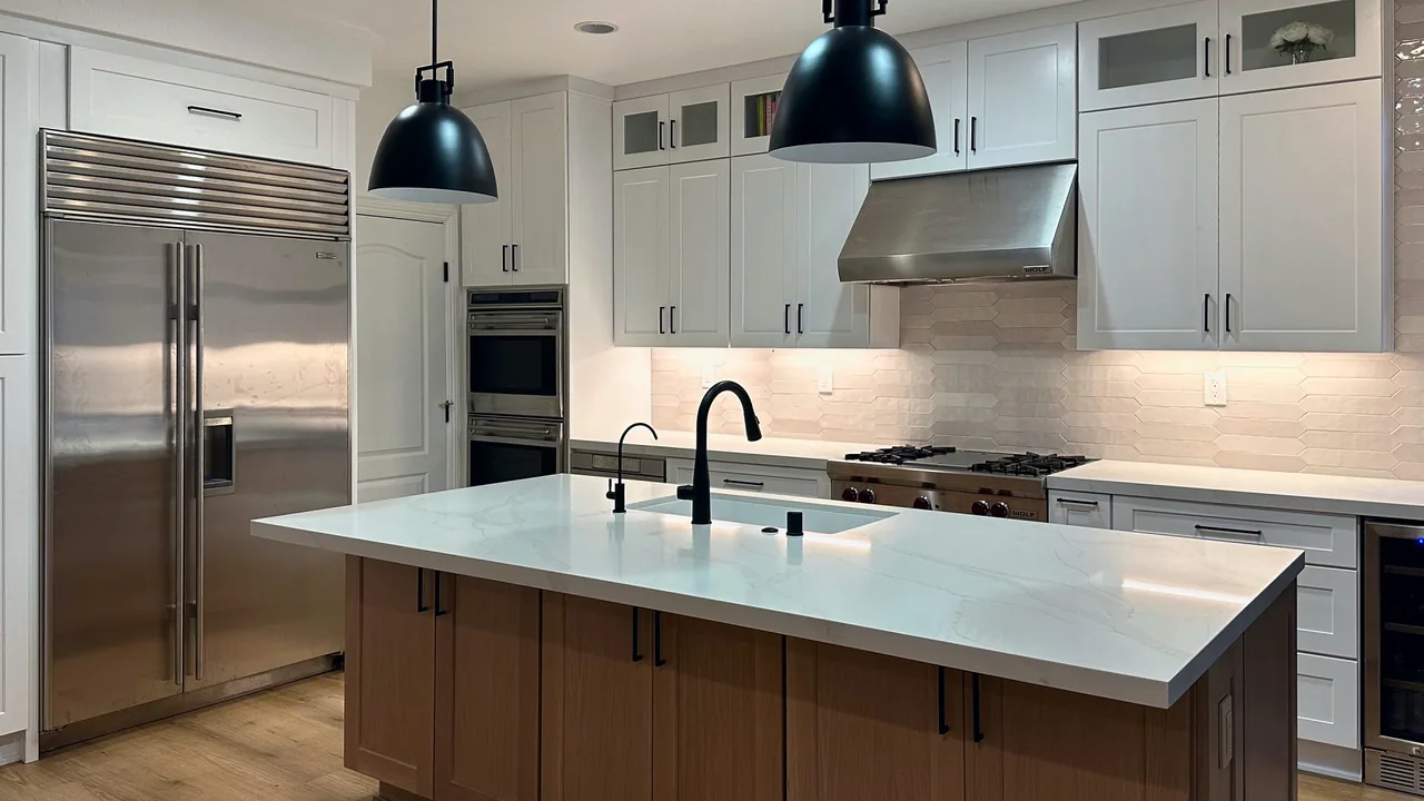 Remodeled kitchen with white shaker cabinets, a stained wood island with a quartz top, two black pendant lights and stainless pro appliances