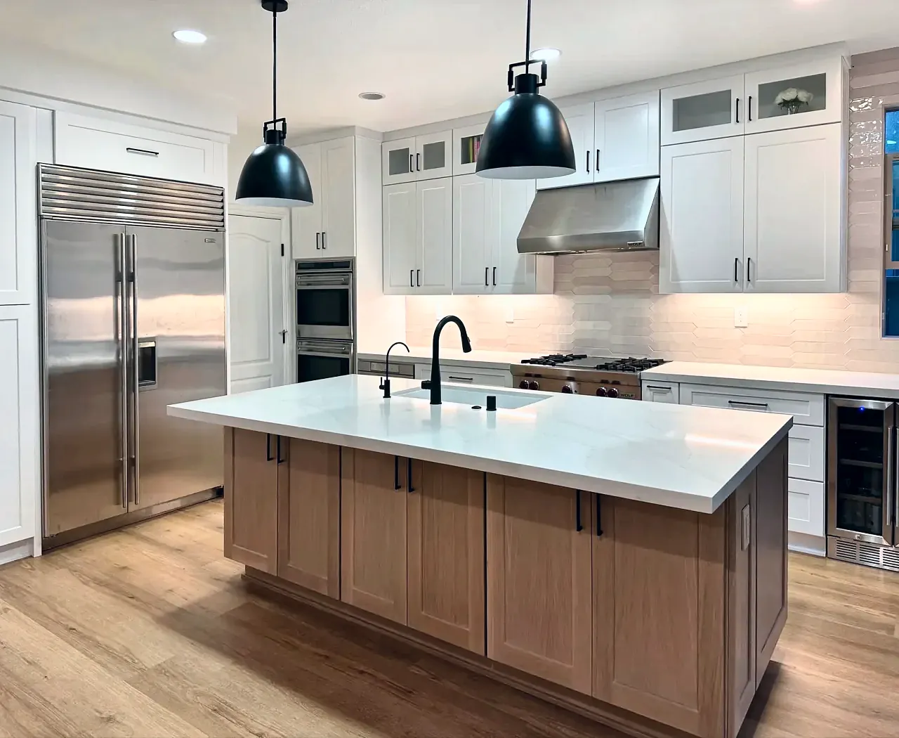 White shaker kitchen with a light oak island and black pendants, designed and built by Seven