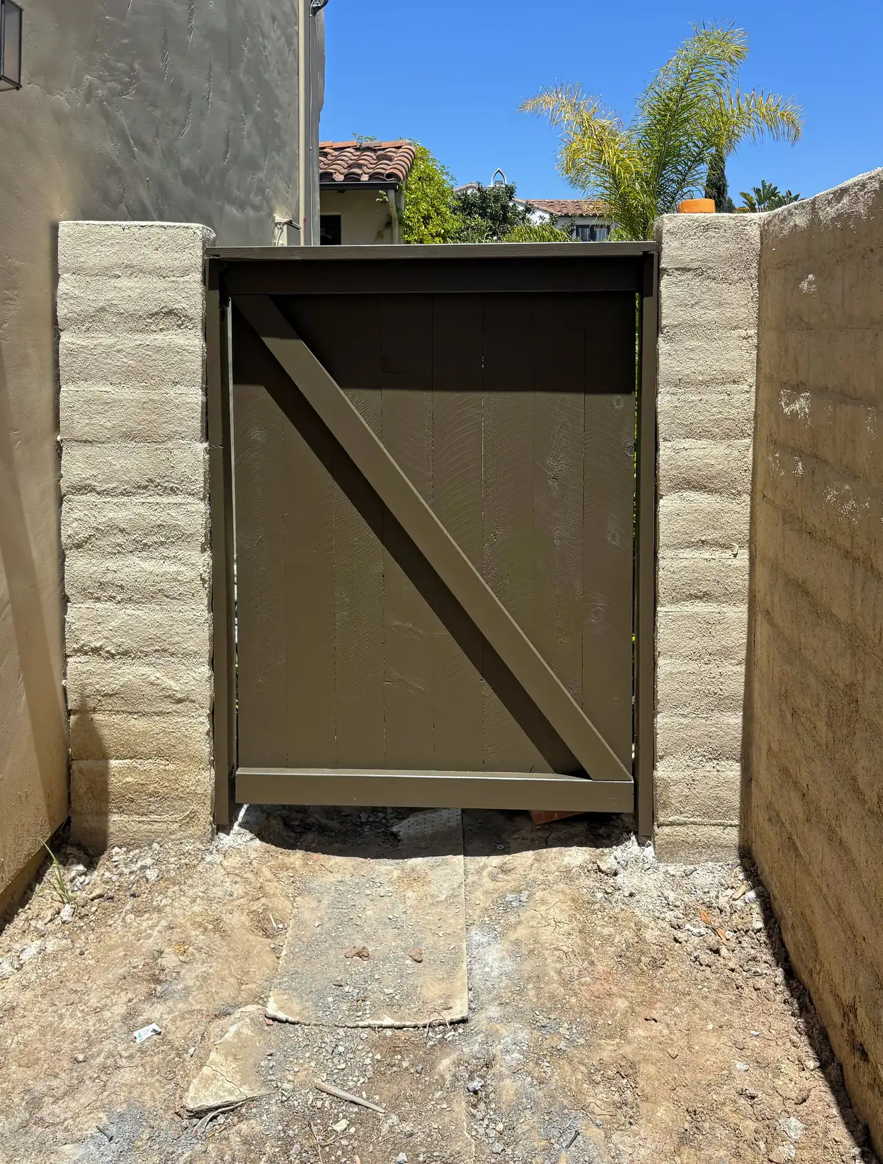 The new wood side gate between block pillars, installed during the pool work