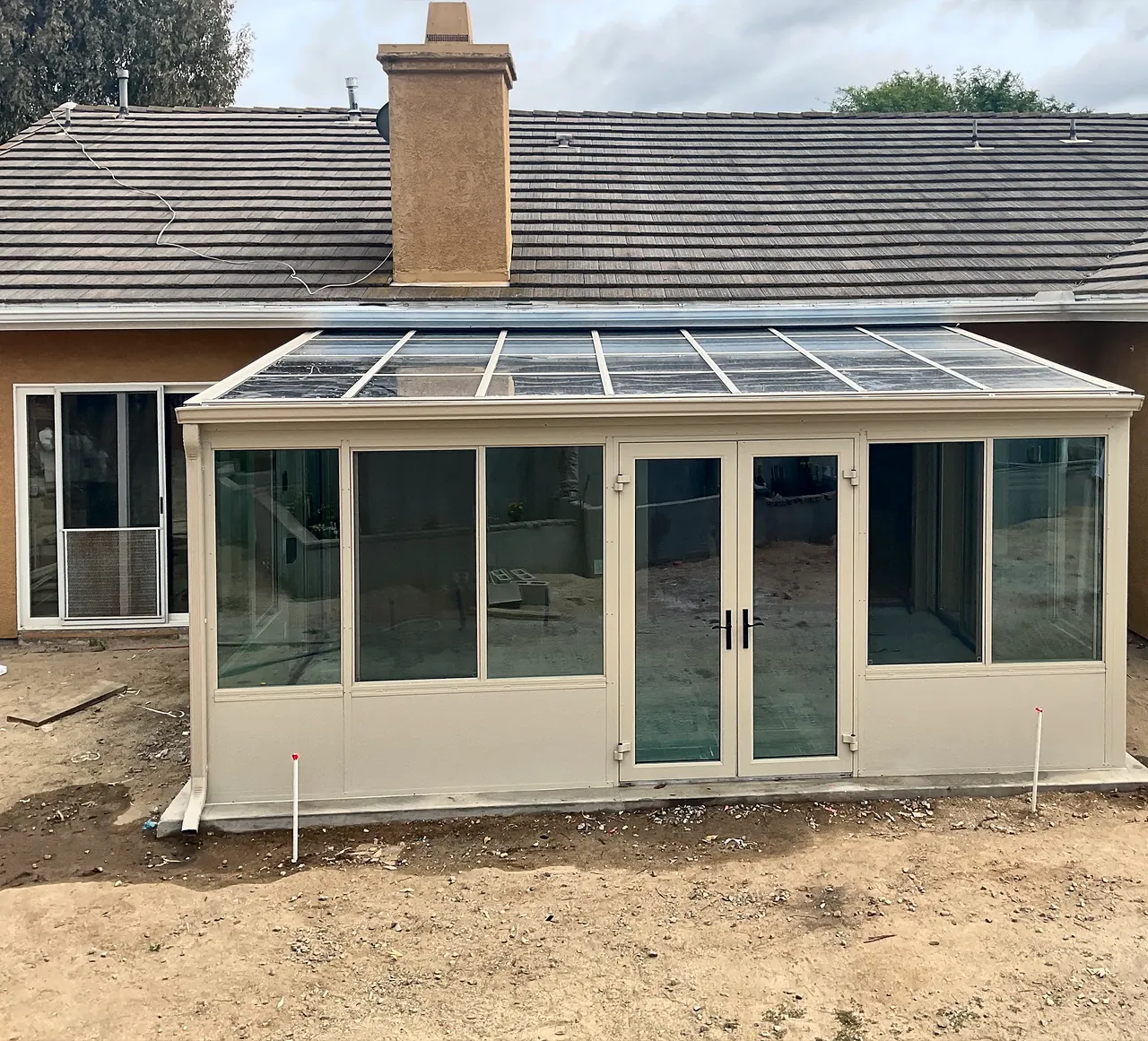 The finished Four Seasons sunroom from the yard, with its glass roof, French doors and sliding windows, before the yard was landscaped