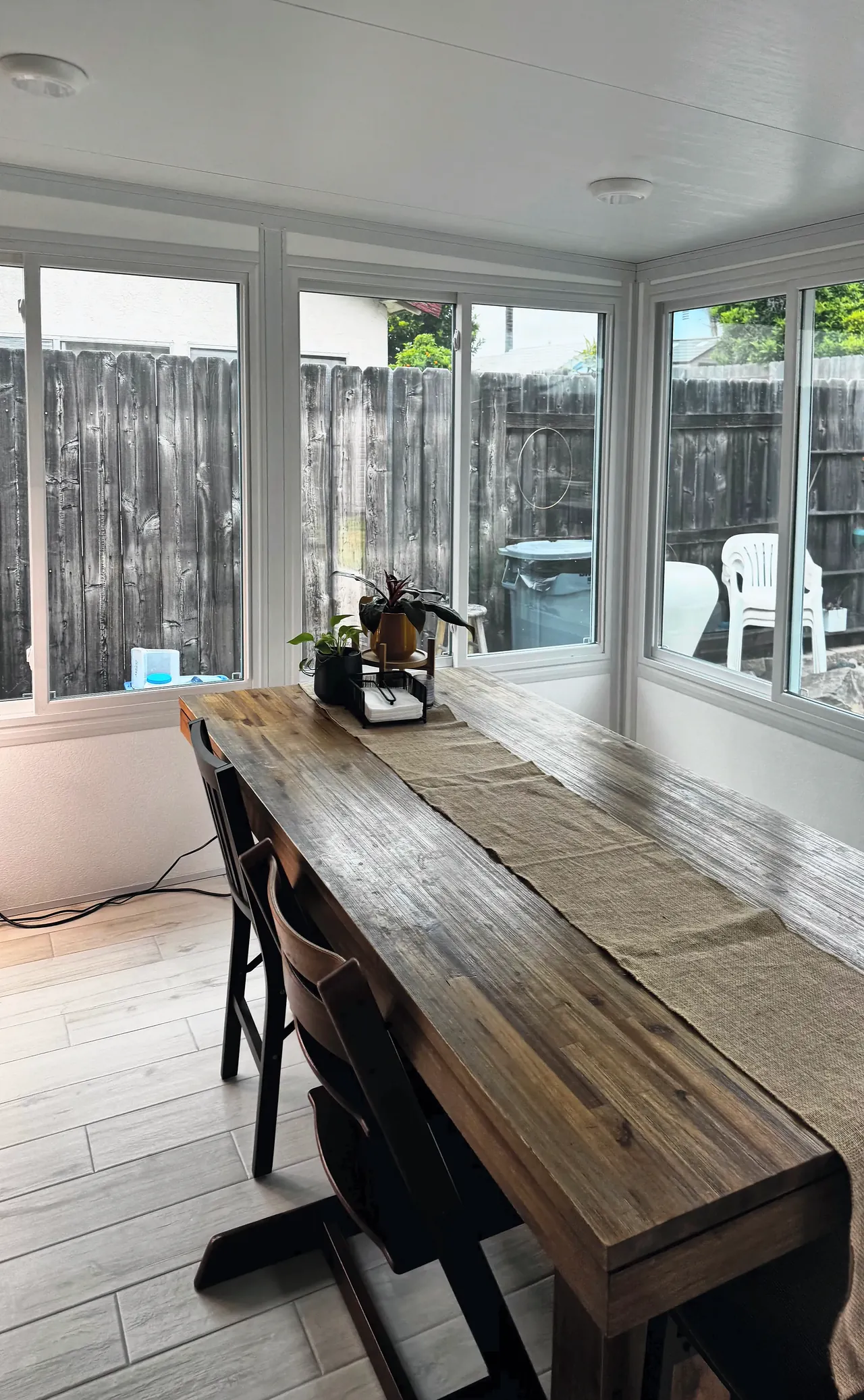 The Mira Mesa sunroom in use as a dining room, with windows on two walls looking out to the yard