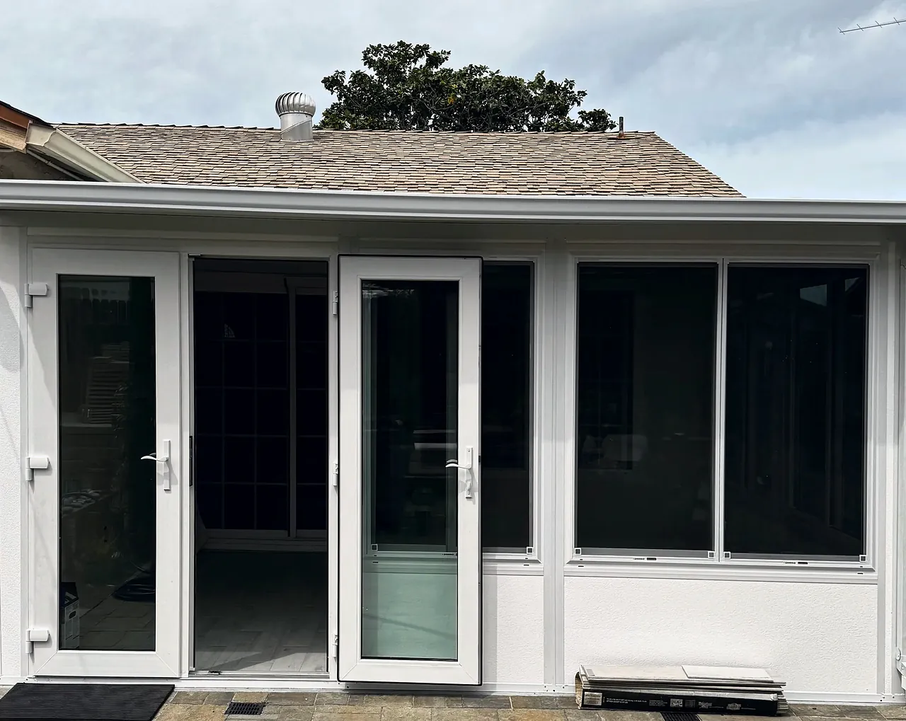 The finished sunroom in the same corner, seen from the same spot, with French doors and sliding windows