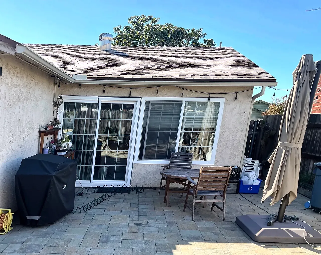 The open patio corner at the back of the house before the sunroom, with a grill and a patio table