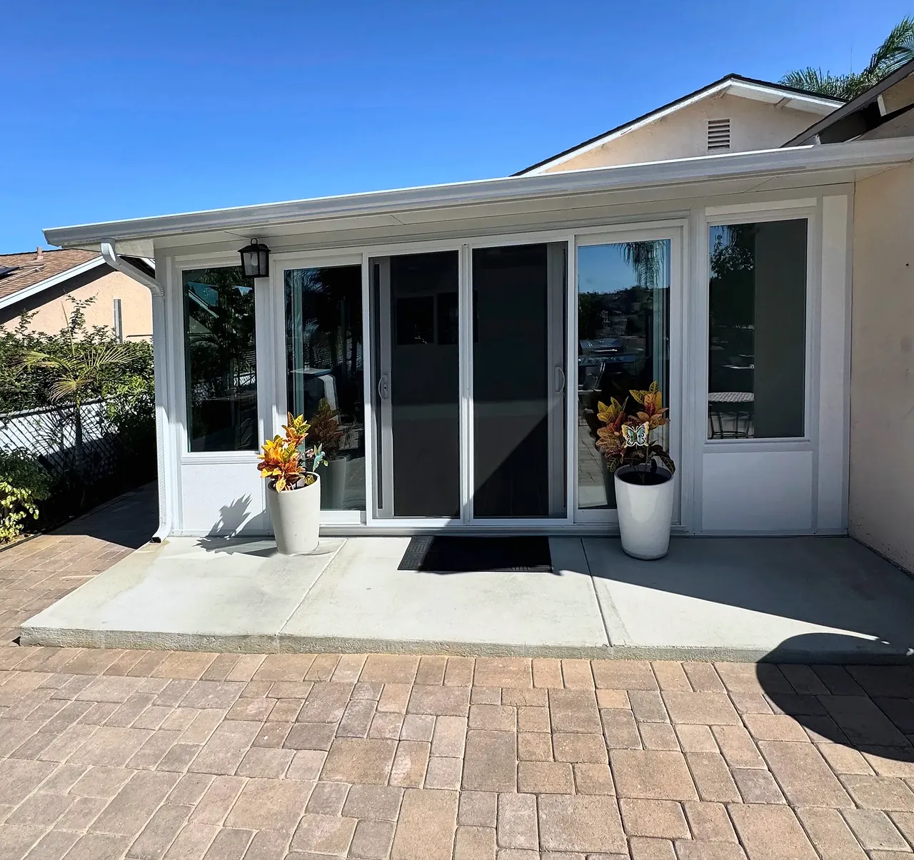 Four Seasons sunroom we built in Vista, seen from the back patio, with a four-panel sliding glass door and a solid white roof